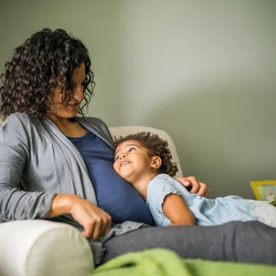 A little child kissing her pregnant mom's belly.