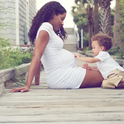 Pregnant Mother with son sitting outdoors.