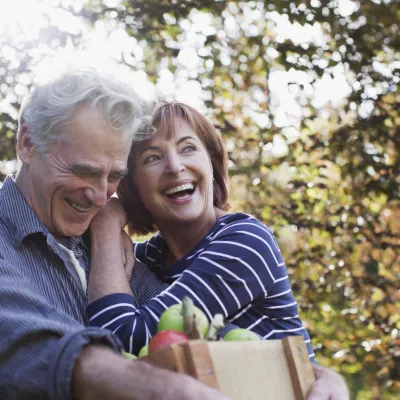 Senior couple smiling and embracing after picking up some apples