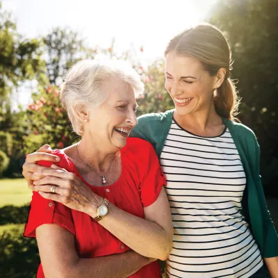 Senior mother and adult daughter walking together outdoors.