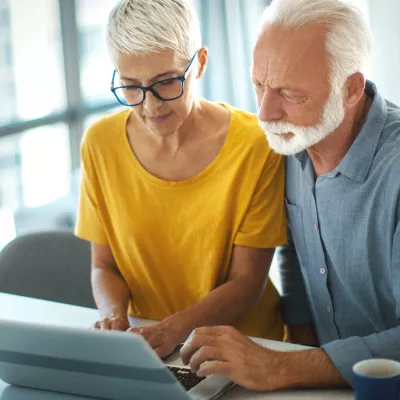 Senior couple viewing a laptop together at the kitchen counter