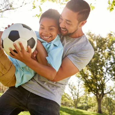 Father and son playing soccer in the park.