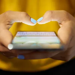 A woman types on a cell phone.