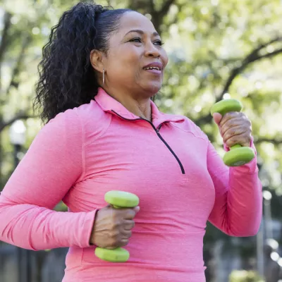 Woman walking outdoors and carrying small hand weights