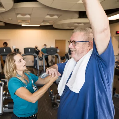 Will Cavins at the Research Institute Raises His Arm as a Trainer Checks His Other Arm