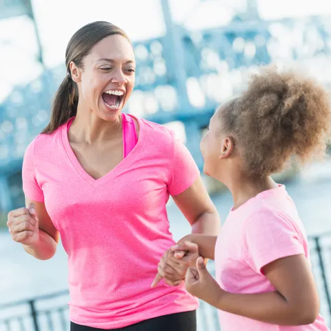Mother and Daughter Laughing as They Jog Together Along The Water Front.