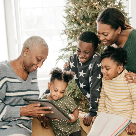 Family looking at photo album next to a Christmas tree
