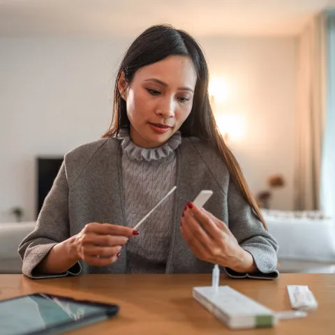 A Woman Checks the Results of an at Home COVID test.