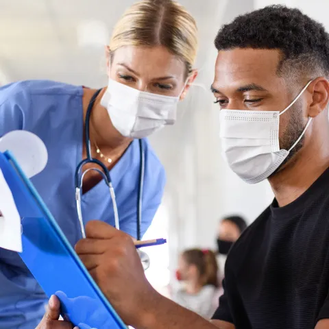 A Patient Fills Out a Form With the Assistance of a Doctor