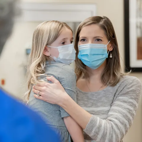 A Mother Holds Her Daughter as She Speaks to a Doctor in the Hospital