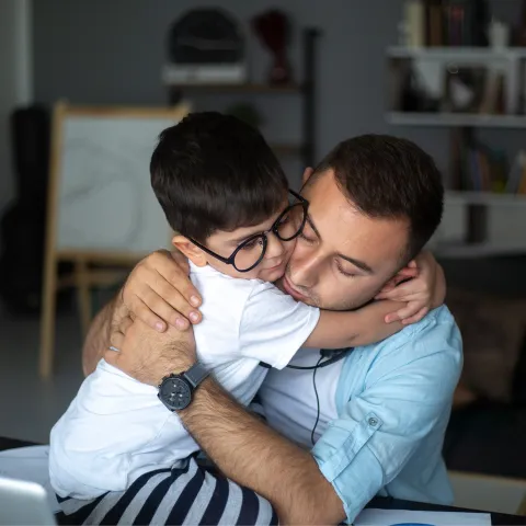 A Father Hugs His Son in a Play Room at Home