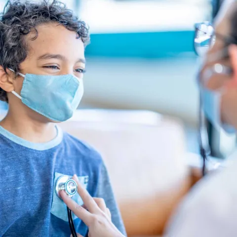 A doctor using her stethoscope on a youthful boy's chest