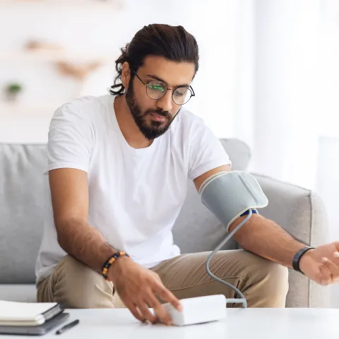 An adult male testing his blood pressure at home