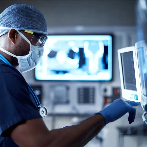 A Doctor Examines a Patient's Information on a Monitor During a Procedure