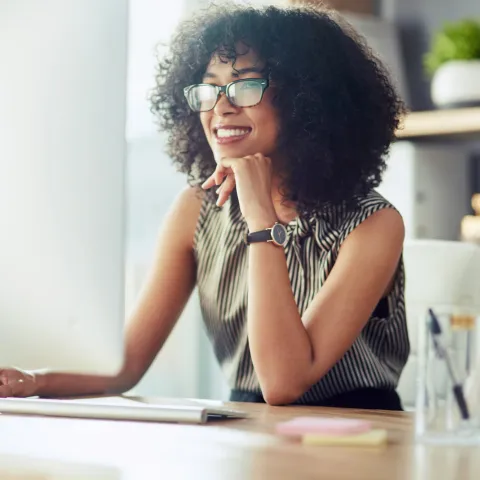 A Woman Smiles as She Reads on Her Computer at Home.