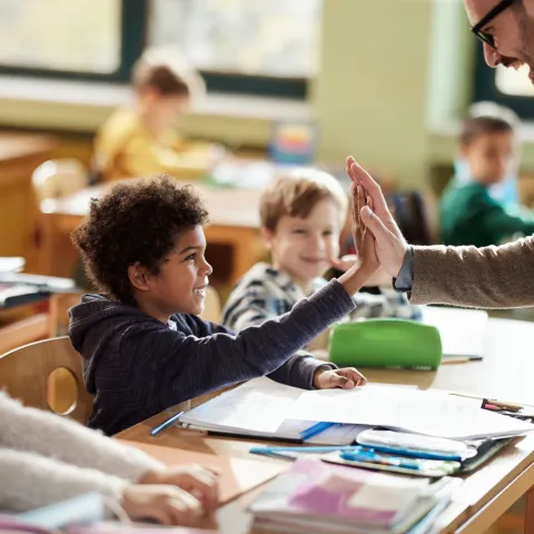 A Student High Fives His Teacher in the Classroom