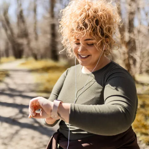 A Woman Checks Her Smart Watch While Going For a Run in the Park