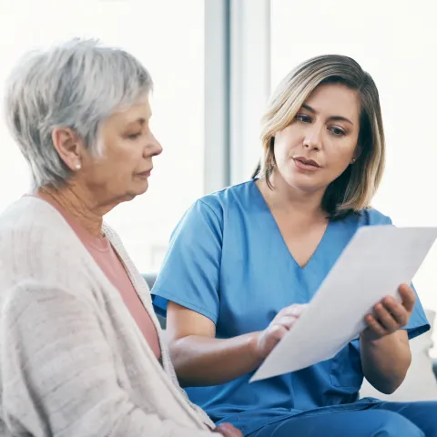A Health Care Provider Goes Over Paperwork with a Patient at the Hospital.