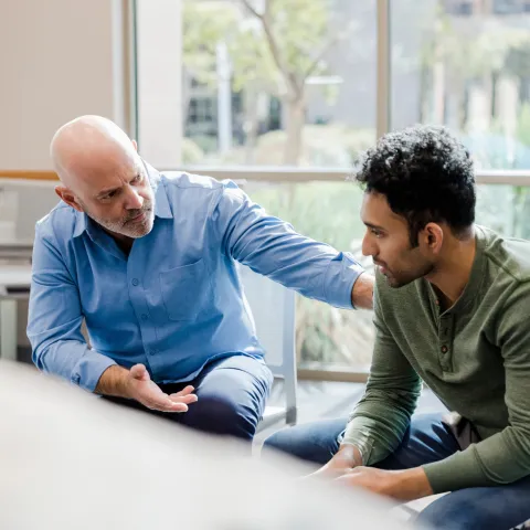 A Therapist Speaks to His Patient and Put's his Hand on His Shoulder