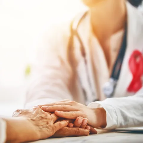 Female doctor placing hand on patient's hand.