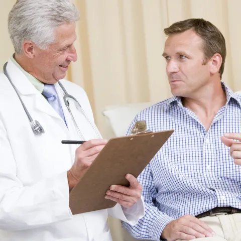A doctor and his male patient (who is reclined) are consulting during an appointment.