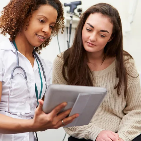 A nurse shows a young woman her test results from a prevenetive screening.