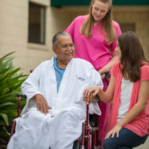 Nurse and visitor talking with a patient. 