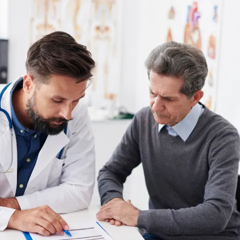 A doctor reviewing test results with a male patient at an appointment.