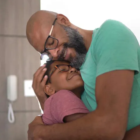 father embracing son at home