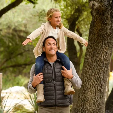A girl sits on her dad's shoulders 