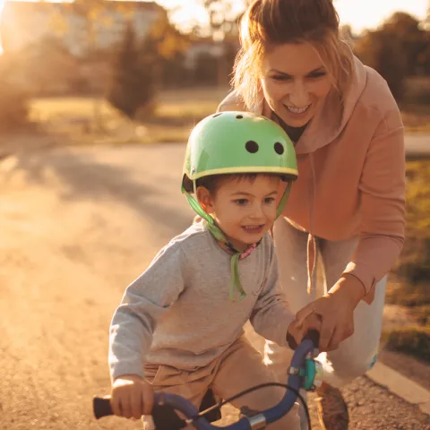 A woman teaches her child to ride a bike.
