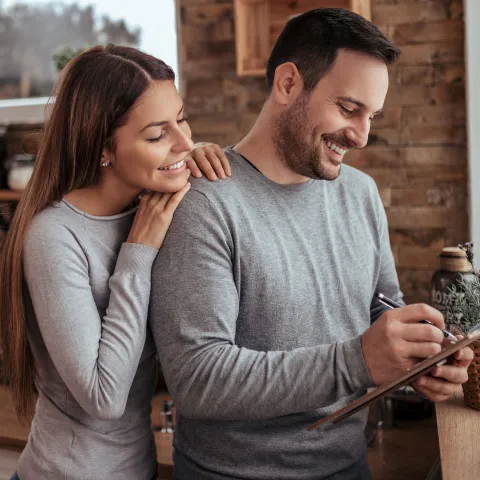A couple making a list together in the kitchen.