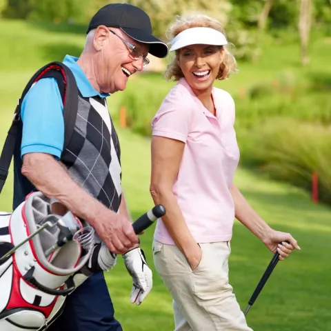 A couple walks the course between holes while golfing.