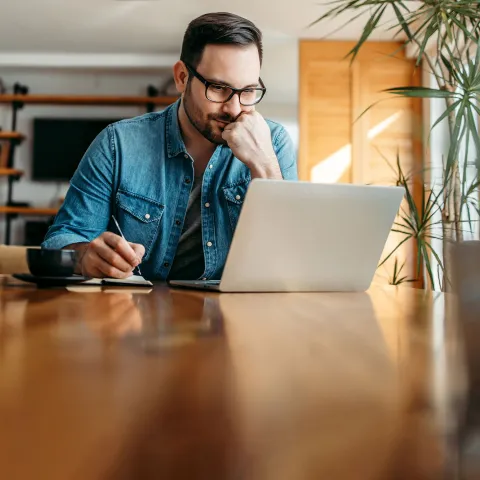 A gentleman indoors and focused on a task on his laptop