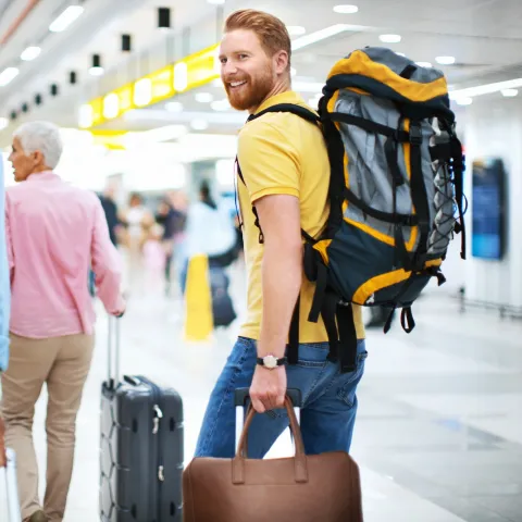 A man wearing a backpack at the airport.
