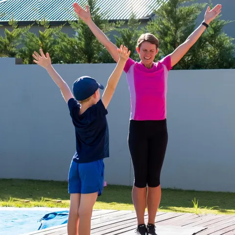 A mom does PE at home with her kids.