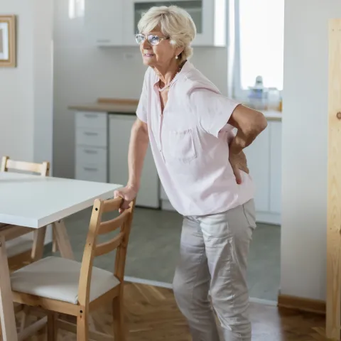 A woman experiencing lower back pain in her home. 