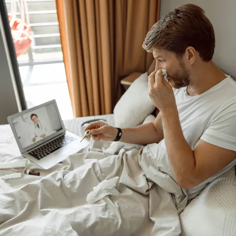 A young man has a remote check up with his doctor from home