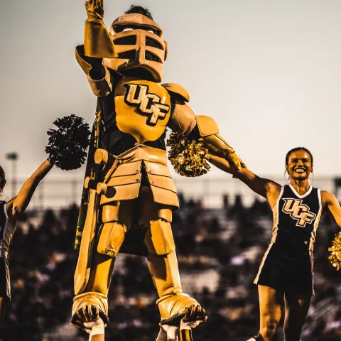 The UCF mascot and cheerleaders during a football game.