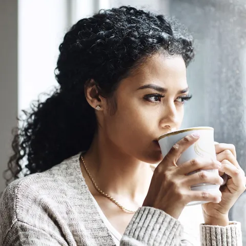 Woman drinking coffee by the window.