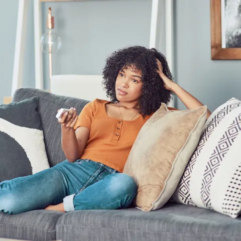 A woman relaxing and watching television at her house