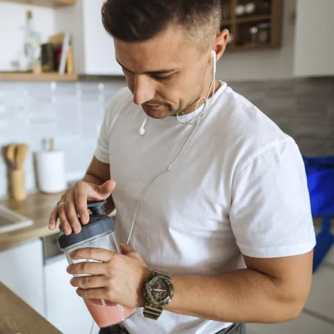 A man making a shake and preparing for a workout.