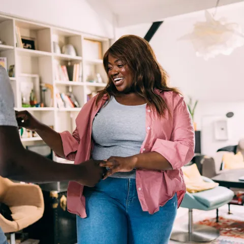 A man and woman holding hands in the living room.