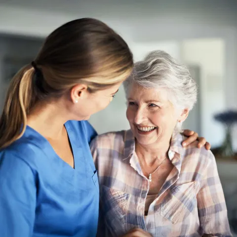 Nurse embracing senior woman at home