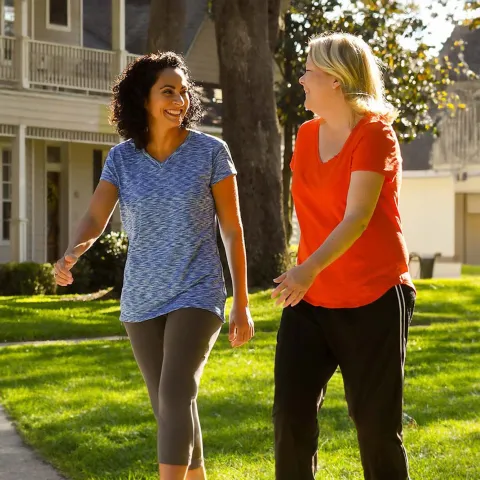 Two women walking and smiling in a neighborhood