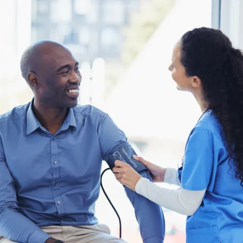 A male patient getting his blood pressure checked by a nurse.