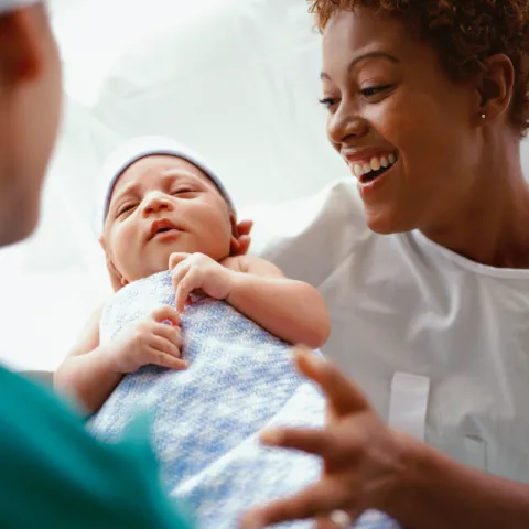 Nurse presents newborn baby to mother.