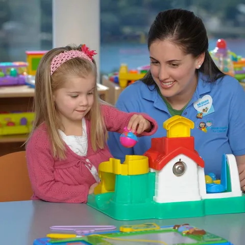 Pediatric specialist and child playing with toy house