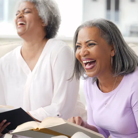 A group of older adults laughing while in a Bible study together.
