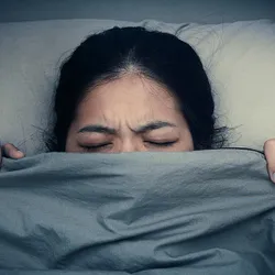 Tired girl sleeping in bed under bed sheets